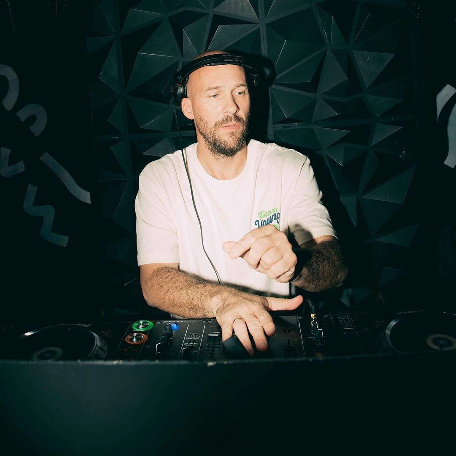 DJ con camiseta blanca mezclando en cabina