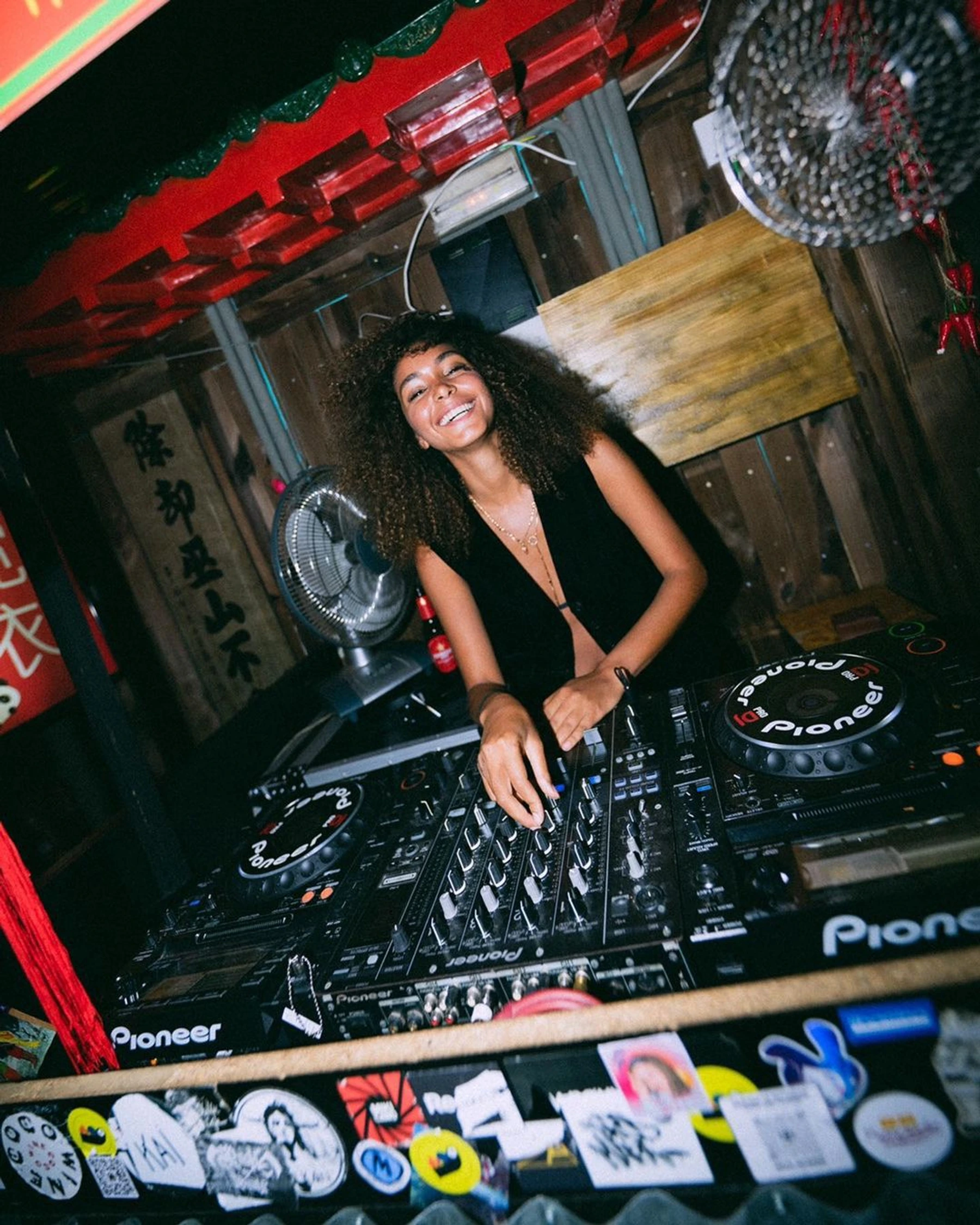 DJ sonriendo tras una mesa de mezclas Pioneer